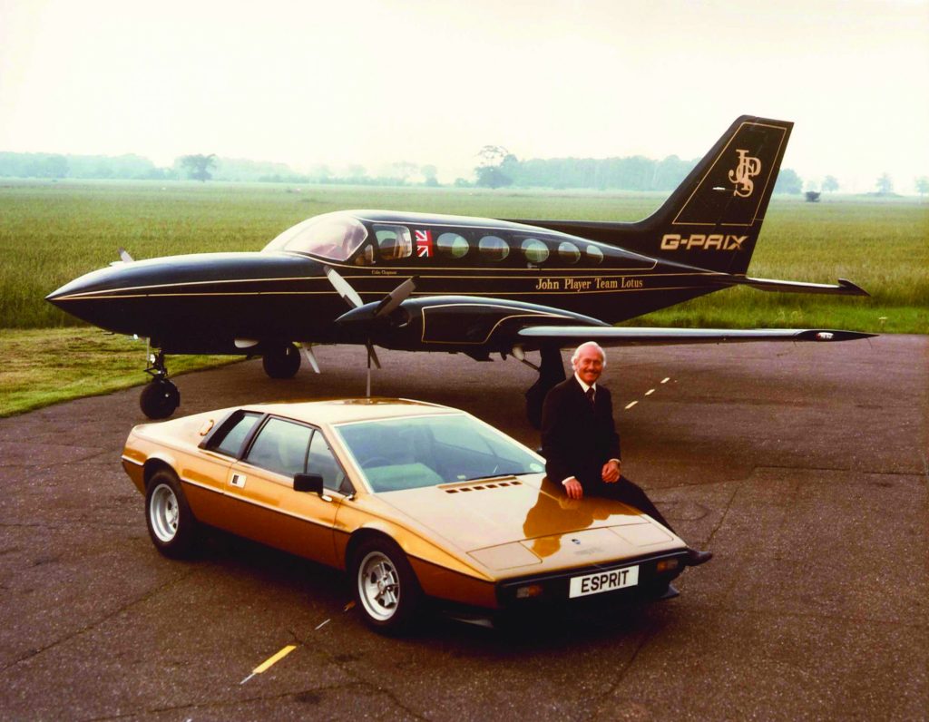 Colin Chapman mit einem Lotus Esprit sowie dem Flugzeug des Teams.